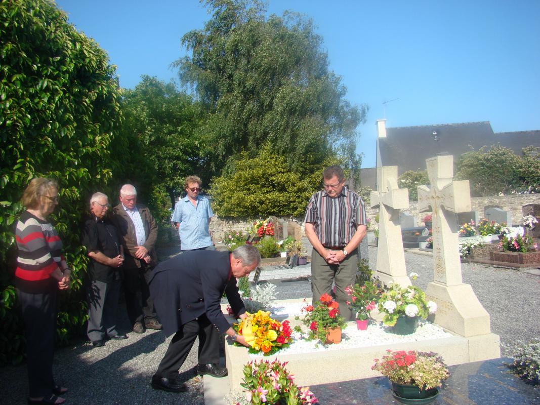 Dominique Le Roux, président du comité de Jumelage de Plomelin pose un plant sur la tombe de Robert Omnès