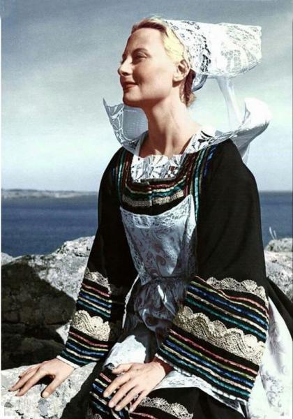 Photo de Michèle Morgan portant le costume et la coiffe de Pont-Aven. La photo a été prise dans la région de Nevez--probablement à la pointe de Trévignon.  Derrière la baie de Concarneau et la pointe de Beg Meil. Auteur inconnu. L'original est en noir et blanc.
